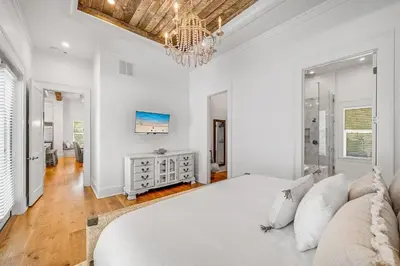 a white bedroom with a bed and a chandelier at Pinecrest Retreat in Inlet Beach