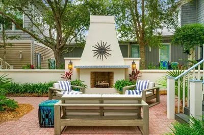 a patio with two chairs and a fireplace at Piccadilly Cottage in Rosemary Beach