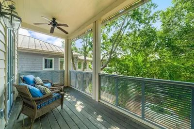a screened porch with a chair and a ceiling fan at Piccadilly Cottage in Rosemary Beach