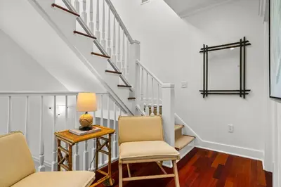 a living room with two chairs and a table and stairs at Piccadilly Cottage in Rosemary Beach