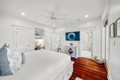 a white bedroom with a large white bed and wooden floors at Piccadilly Cottage in Rosemary Beach
