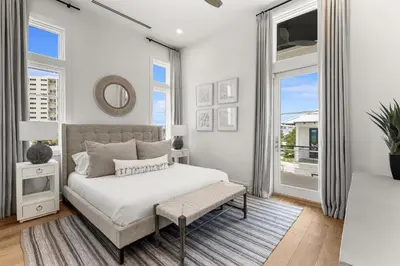 a bedroom with white walls and a bed and windows at On Deck in Panama City Beach