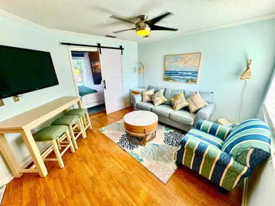 a living room with a couch and a flat screen tv at Beach Across Street, Walk to Restaurants, 2 Pools, Beach Gear in Panama City Beach