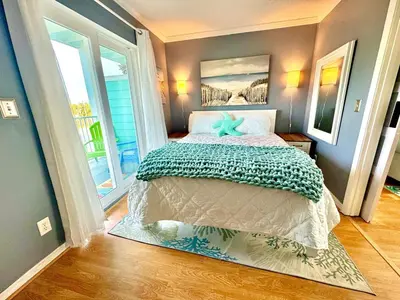 a bedroom with a bed and a large window at Beach Across Street, Walk to Restaurants, 2 Pools, Beach Gear in Panama City Beach
