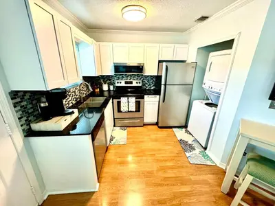a kitchen with white appliances and a wooden floor at Beach Across Street, Walk to Restaurants, 2 Pools, Beach Gear in Panama City Beach