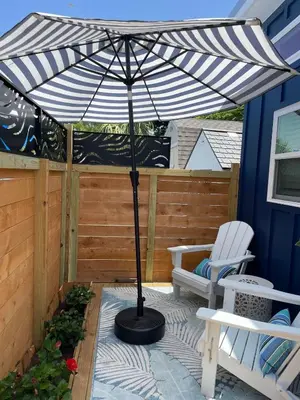 a patio with a black and white umbrella and a chair at The Blue Umbrella at the Beach in Panama City Beach