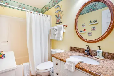 a bathroom with a sink and a toilet and a mirror at Cheerful 1-bedroom townhouse with spacious loft in Panama City Beach