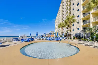 a swimming pool at the beach with chairs and a building at Beach and Pool Access Regency Towers Condo in PCB! in Panama City Beach