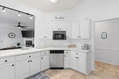 a kitchen with white cabinets and a sink and a microwave at Pet Friendly Beach House - Baby Blue Heron by Panhandle Getaways in Panama City Beach