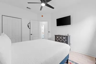 a white bedroom with a bed and a ceiling fan at Pet Friendly Beach House - Baby Blue Heron by Panhandle Getaways in Panama City Beach