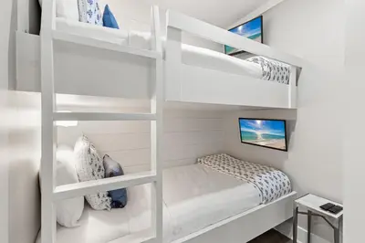 a white bunk room with a bed and a tv at A115 The Fuller View at Watersound in Santa Rosa Beach