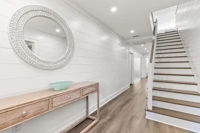 a hallway with a staircase and a mirror on the wall at A115 The Fuller View at Watersound in Santa Rosa Beach