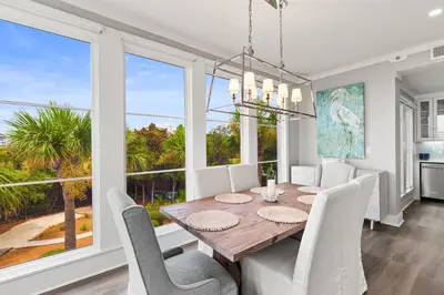 a dining room with a table and chairs and large windows at A115 The Fuller View at Watersound in Santa Rosa Beach