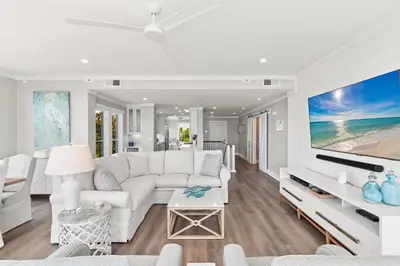 a living room with a white couch and a tv at A115 The Fuller View at Watersound in Santa Rosa Beach