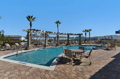 a swimming pool with chairs and a table and a wooden at Shell We Stay (3/2.5) in Panama City Beach