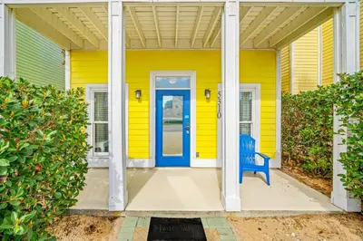 a blue bench sitting in front of a yellow house at PCB Private Pool Home, Sleeps 14, Dog Friendly, Near Beach in Panama City Beach