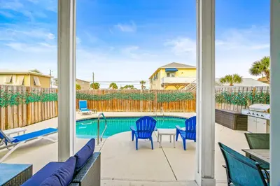 a patio with blue chairs and a swimming pool at PCB Private Pool Home, Sleeps 14, Dog Friendly, Near Beach in Panama City Beach