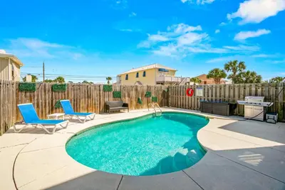 a swimming pool with two chairs and a table and a fence at Beach House w/ Private Pool Near PCB | Dog Friendly in Panama City Beach