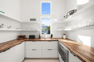 a kitchen with white cabinets and a wooden counter top at 30a Gulf-View Gem | Stay Gold in Santa Rosa Beach