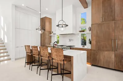 a kitchen with wooden cabinets and a kitchen island with chairs at 30a Gulf-View Gem | Stay Gold in Santa Rosa Beach