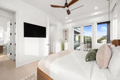 a white bedroom with a large bed and a flat screen tv at 30a Gulf-View Gem | Stay Gold in Santa Rosa Beach