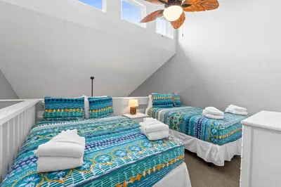 two twin beds in a room with a ceiling fan at Quiet West End PCB Condo w/ Gulf Views, Pool & Easy Beach Access in Panama City Beach