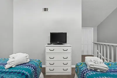 a bedroom with two beds and a tv on a dresser at Quiet West End PCB Condo w/ Gulf Views, Pool & Easy Beach Access in Panama City Beach