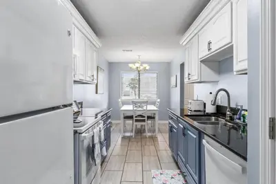 a kitchen with white cabinets and a sink and a table at Pet-Friendly Coastal Townhome | Walk to Beach & Local Dining in Panama City Beach
