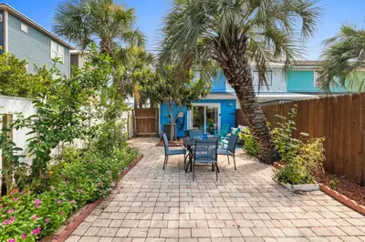 a patio with a table and chairs and palm trees at Pet-Friendly Coastal Townhome | Walk to Beach & Local Dining in Panama City Beach