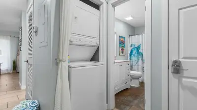 a white bathroom with a toilet and a sink at Renovated Condo 4-Min Walk to Beach & Pools in Panama City Beach