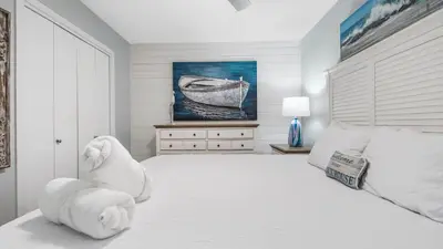 a white bedroom with a large bed with a white headboard at Renovated Condo 4-Min Walk to Beach & Pools in Panama City Beach