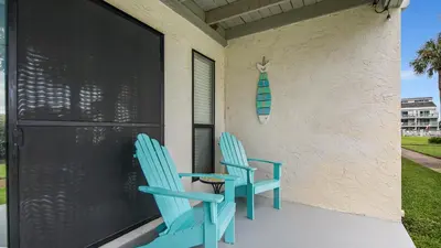 two blue chairs sitting on the porch of a house at Renovated Condo 4-Min Walk to Beach & Pools in Panama City Beach