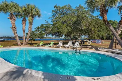 a swimming pool with chairs and palm trees at Pirates Cove Inlet Unit H (0/1) in Panama City Beach