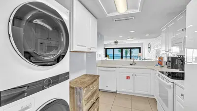 a white kitchen with a washer and dryer in it at Low Floor - Remodeled - Beachfront - FLPCB65 in Panama City Beach