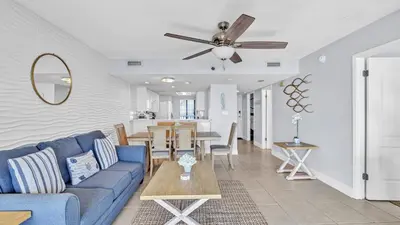 a living room with a blue couch and a table at Low Floor - Remodeled - Beachfront - FLPCB65 in Panama City Beach