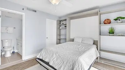 a white bedroom with a bed and a toilet at Low Floor - Remodeled - Beachfront - FLPCB65 in Panama City Beach