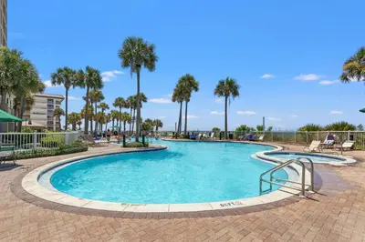 a swimming pool at a resort with palm trees at Grand Panama Beach Resort by Panhandle Getaways in Panama City Beach