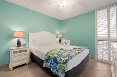 a bedroom with a bed and a nightstand and a window at Direct Gulf View 2BR Paradise Found in Panama City Beach