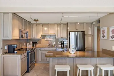 a kitchen with white cabinets and a counter with stools at Direct Gulf View 2BR Paradise Found in Panama City Beach