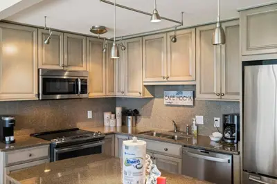 a kitchen with wooden cabinets and stainless steel appliances at Direct Gulf View 2BR Paradise Found in Panama City Beach