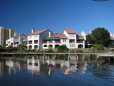 a large white building next to a body of water at 3BR Grand Lagoon Front Townhome - Private Dock, Resort Amenities & Beach Walk in Panama City Beach