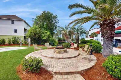 a fire pit in a yard with chairs and a palm tree at 3BR Grand Lagoon Front Townhome - Private Dock, Resort Amenities & Beach Walk in Panama City Beach