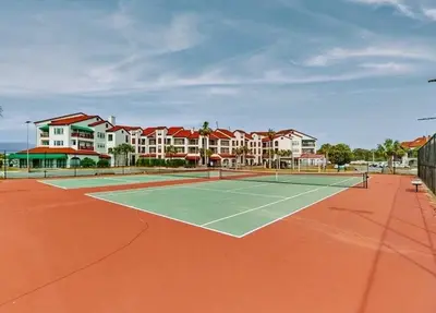 a tennis court in front of a apartment complex at 3BR Grand Lagoon Front Townhome - Private Dock, Resort Amenities & Beach Walk in Panama City Beach