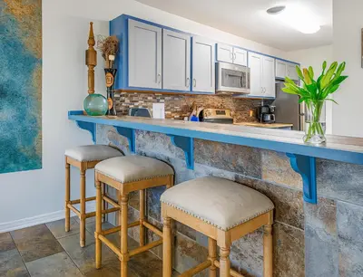 a kitchen with blue counter tops and stools at 3BR Grand Lagoon Front Townhome - Private Dock, Resort Amenities & Beach Walk in Panama City Beach