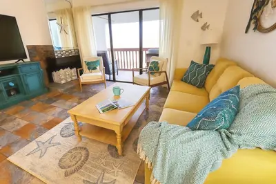 a living room with a yellow couch and a table at 3BR Grand Lagoon Front Townhome - Private Dock, Resort Amenities & Beach Walk in Panama City Beach