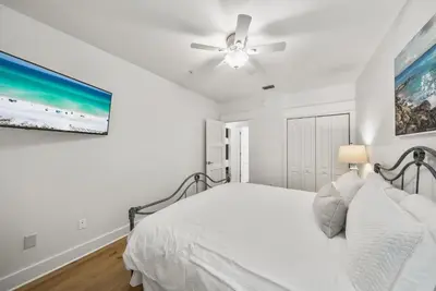 a white bedroom with a bed and a ceiling fan at Lagoon Lounge in Seacrest