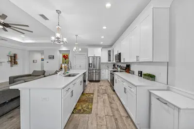 a white kitchen with white cabinets and a couch at New Construction - West End PCB - Gated Neighborhood - FLPCB63 in Panama City Beach