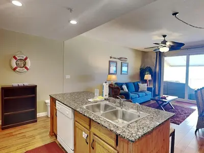 a kitchen with a sink and a living room at Sterling Reef #106 in Panama City Beach