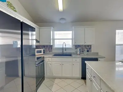 a kitchen with white cabinets and a sink at Captain Bennetts Cove in Panama City Beach