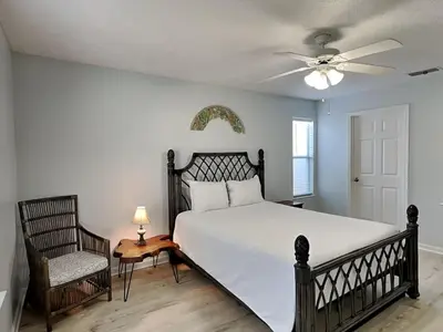 a bedroom with a bed and a ceiling fan and a chair at Captain Bennetts Cove in Panama City Beach